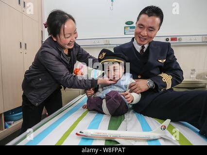 The mother, right, of the four-year-old legless boy Xiao Feng helps her son put on the hat of a pilot of China Eastern Airlines, right, at Zhongnan Ho Stock Photo