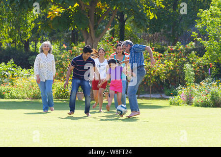 Family playing football in lawn Stock Photo