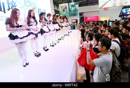 A crowd of visitors take photos of showgirls dressed in maid costumes during the 13th China Digital Entertainment Expo, also known as ChinaJoy 2015, i Stock Photo