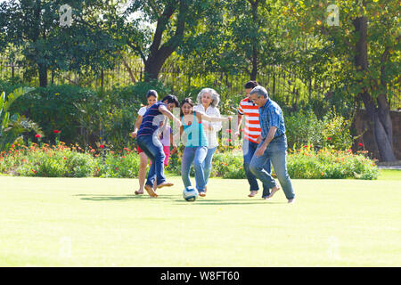 Family playing football in lawn Stock Photo