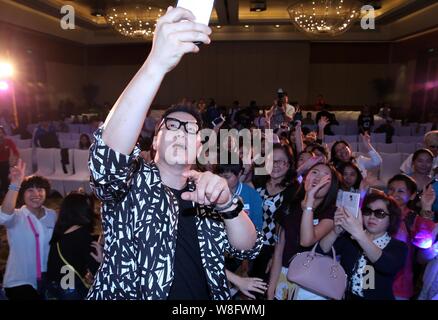 South Korean singer Jeong Soon-won, left, better known by his stage name The One, takes selfies with fans during a press conference for his Chinese al Stock Photo