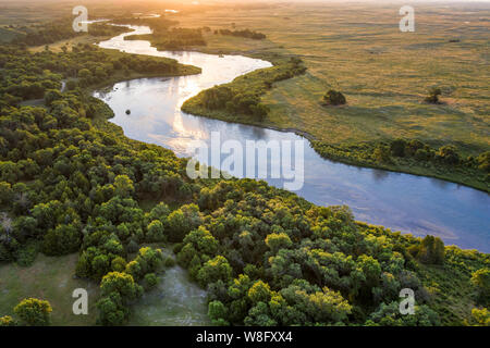 sunrise over Dismal River meandering through Nebraska Sandhills at Nebraska National Forest, aerial view of summer scenery Stock Photo