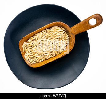 whole, organic oat groats on a rustic wooden scoop against an isolated black plate Stock Photo