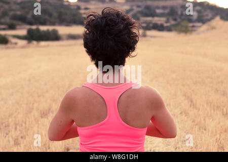 Young girl meditating and practicing yoga at sunset in an open field. Healthy concept Stock Photo