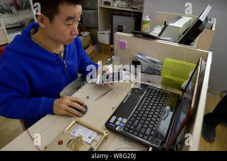 A Chinese technician backs up all the data of an Apple iPhone 6 Plus 16GB smartphone before it is upgraded for storage boost at a mobile phone repair Stock Photo