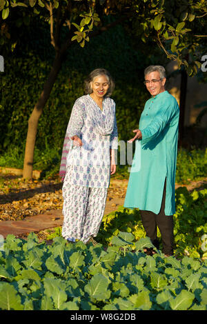 Old man showing his vegetable garden to his wife Stock Photo