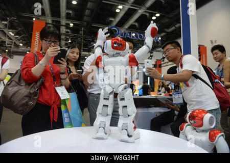 Visitors look at a humanoid intelligent robot dancing during the 2015 Global Mobile Internet Conference (GMIC 2015) in Beijing, China, 29 April 2015. Stock Photo