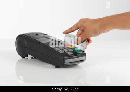 Person hand swiping credit card through machine Stock Photo