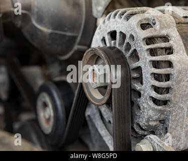 A worn, old serpentine drive belt for motor on alternator pulley on automobile engine Stock Photo