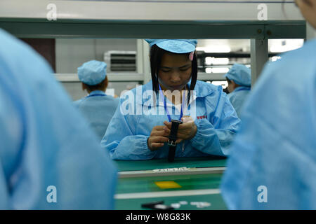 --FILE--A Chinese worker assembles a smart watch on the assembly line ...