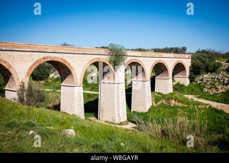 Beautiful old stone bridge of abandoned railway crossing a small river. Puglia region, Italy Stock Photo