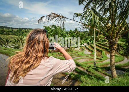 Woman takes picture with a smartphone on rice terrace,  on Bali streets, Indonesia Stock Photo