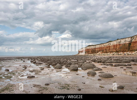 Hunstanton striped cliffs, with rounded boulders on the beach. Stock Photo