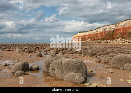 Hunstanton striped cliffs, with rounded boulders on the beach. Stock Photo