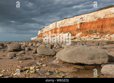 Hunstanton striped cliffs, with rounded boulders on the beach. Stock Photo