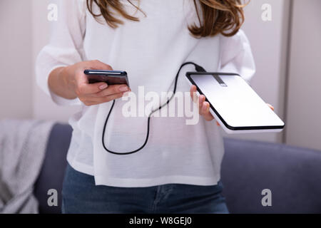 Mid-section Of Woman Using External Hard Disk For Data Transfer Stock Photo