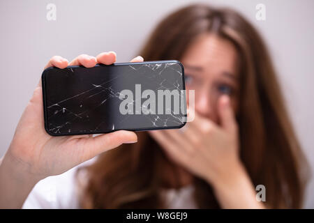 Woman Hand Holding Smartphone With Cracked Screen Stock Photo