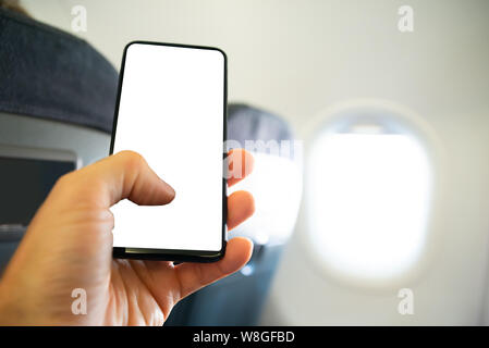 Close-up Of Person's Hand Using Mobile Phone With Blank Screen In Airplane Stock Photo