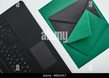 Isolated kraft paper sheet and envelopes on a white background next to a laptop. Horizontal flat-lay Stock Photo