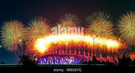 Fireworks explode over the Beijing National Stadium, back, also known as the Bird's Nest, in the Olympic Green in Beijing, China, 10 November 2014. Stock Photo