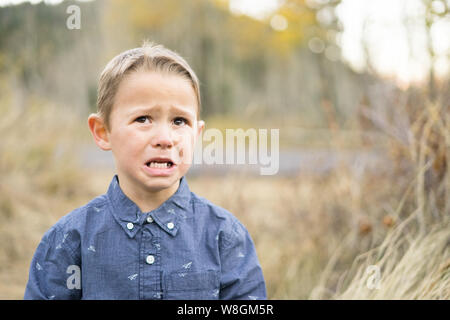 A little five year old boy cries while taking family pictures outdoors Stock Photo