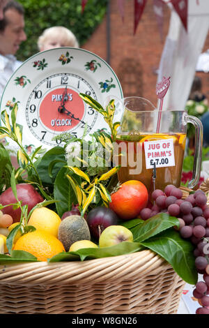Jug of Pimm's with fresh fruit in a basket at a summer garden party, capturing a classic British outdoor refreshment scene. Stock Photo