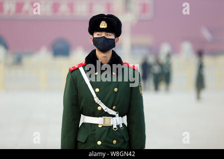 A Chinese paramilitary policeman wearing a face mask stands guard on the Tiananmen Square in heavy smog in Beijing, China, 19 December 2015.  Thick sm Stock Photo