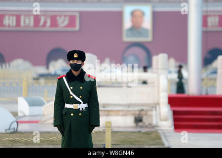 A Chinese paramilitary policeman wearing a face mask stands guard on the Tiananmen Square in heavy smog in Beijing, China, 19 December 2015.  Thick sm Stock Photo