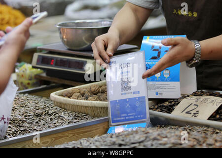 --FILE--A customer uses his smartphone to scan a QR code offered by a vendor to pay by Alipay at a free market in Qingdao city, east China's Shandong Stock Photo