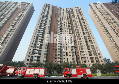 Fire engines pass by high-rise residential apartment buildings damaged in the massive explosions in Binhai New Area in Tianjin, China, 13 August 2015. Stock Photo