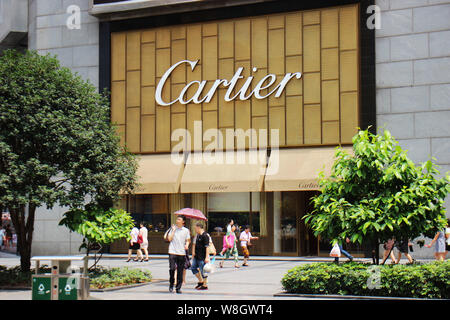 --FILE--Pedestrians walk past a boutique of Cartier in Chongqing, China, 27 June 2015.   The gold and diamonds of Cartier jewelry are so popular with Stock Photo