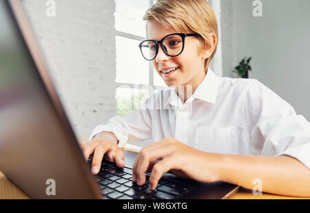 Smiling boy in glasses using laptop Stock Photo