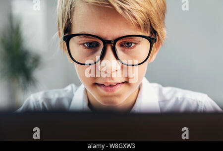 Concentrated boy in glasses gazing at the computer screen Stock Photo