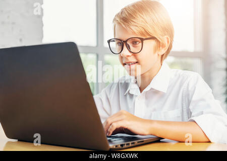 Concentrated kid in glasses using laptop Stock Photo