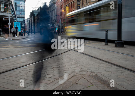 Manchester, United Kingdom - July 15 2019: Unrecognizable people on the move in  the streets on Manchester in United Kingdom and moving trains. Motion Stock Photo