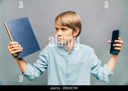 Kid making a hard choice between book and smartphone Stock Photo