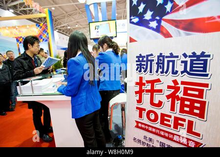 --FILE--Chinese employees serve visitors at the booth of TOEFL (Test of English as a Foreign Language) during the 2014 China International Education E Stock Photo