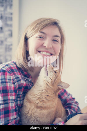 Red tabby cat is kissing a young beautiful girl, closeup Stock Photo