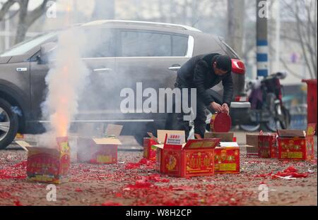 A man prepares to ignite fireworks and firecrackers on a street during Spring Festival to celebrate the Chinese Lunar New Year in Nantong city, east C Stock Photo