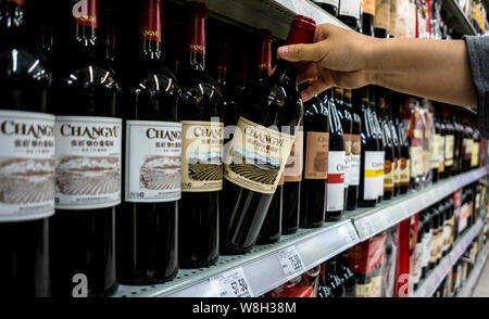 --FILE--A customer shops for a bottle of Changyu dry red wine at a supermarket in Beijing, China, 27 April 2014.   Yantai Changyu Pioneer Wine Company Stock Photo