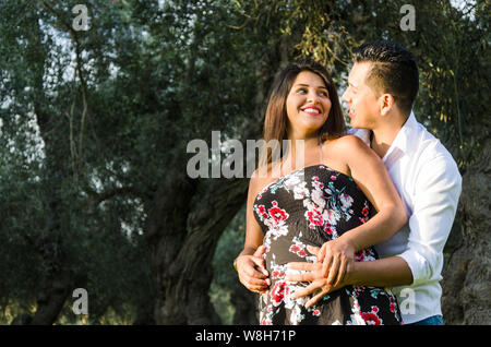 Happy and young pregnant couple hugging in nature, outdoors, waiting for a baby Stock Photo
