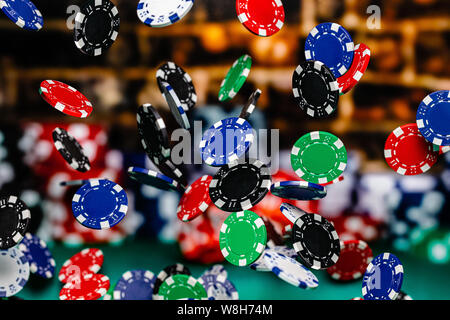 Red, Blue, Black and Green Clay Poker Chips cascading in front of a background of stacked poker chips.  Depth of field is medium, so many chips are in Stock Photo