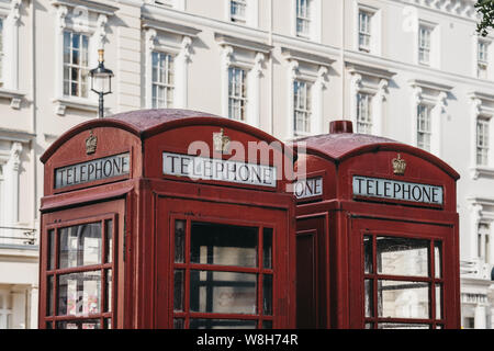 Low angle view of two iconic British red telephone boxes against white buildings, selective focus. Stock Photo