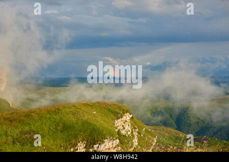 Rainbow over a mountain valley with fog in the foreground. Stock Photo