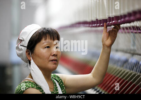 --FILE--A female Chinese worker handles production of yarn at a garment factory in Huaibei city, east China's Anhui province, 1 July 2015.   China¯s e Stock Photo