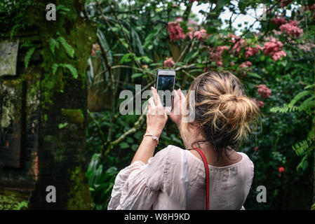 BALI, INDONESIA - JANUARY 10, 2018: Woman takes picture with a iphone 8 plus outdoors on Bali streets, Indonesia Stock Photo