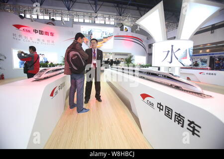 --FILE--Chinese visitors look at models of CRH (China Railway High-speed) bullet trains on display at the stand of CSR (China South Locomotive & Rolli Stock Photo