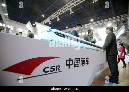 --FILE--Chinese visitors look at models of CRH (China Railway High-speed) bullet trains on display at the stand of CSR (China South Locomotive & Rolli Stock Photo