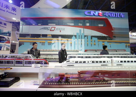 --FILE--Chinese visitors look at models of CRH (China Railway High-speed) bullet trains and subway trains on display at the stand of China CNR Corpora Stock Photo