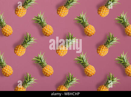 Colorful fruit pattern of fresh pineapples on pink background, top view Stock Photo